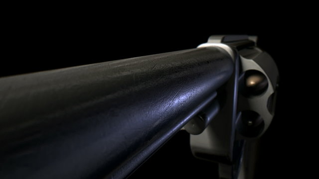 An extreme close view pan back of an old metal pistol with a wooden handle pointed towards the camera on an isolated white background