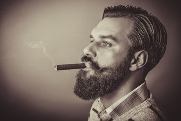 handsome young man with retro look smoking a cigar