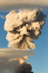 A massive eruption from a volcano on a mountain, sending plumes of ash and smoke into the sky, creating hazardous conditions with dark clouds.