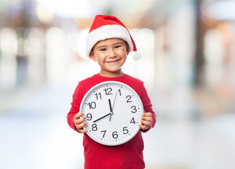 portrait of a little boy on christmas time holding a big clock