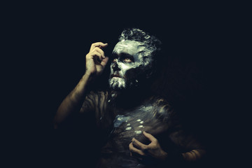 wild man with white painted face and full body black paint