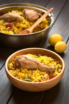 Chicken paella, a traditional Valencian (Spanish) rice dish made of rice, chicken, peas and capsicum , photographed with natural light (Selective Focus, Focus on the chicken thigh)