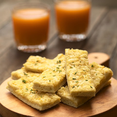 Fresh homemade garlic and cheese sticks made of a yeast dough served on wooden board, sprinkled with fresh thyme leaves (Selective Focus, Focus one third into the upper garlic stick)