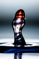 Behold the mesmerizing spectacle of a vibrant red water drop colliding with a bouncing column a...