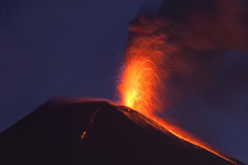 A fiery eruption lights up the night sky over Ecuador's volcanic crater, resembling a mini...