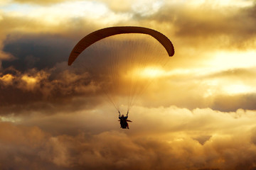 A vibrant image of a tandem paragliding adventure at dusk, with intense colors and postproduction enhancing the parachute's beauty.