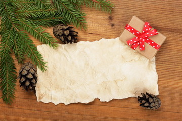 Christmas card. Blank Old Paper Sheet with Christmas tree branches and vintage gift on wooden background