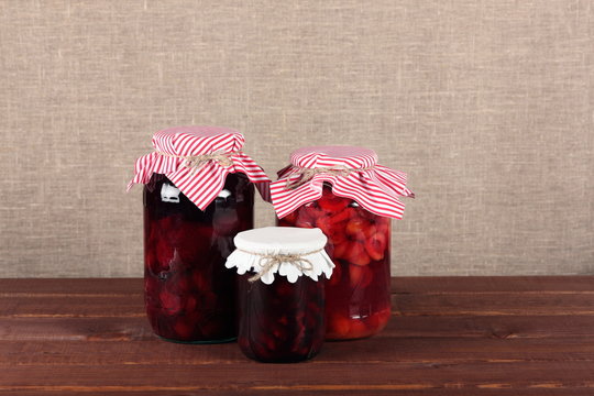 Glass jars with canned fruits on rustic wooden table