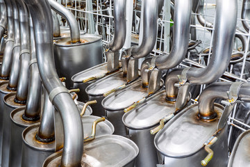 A galvanized exhaust pipe being welded in a manufacturing facility, part of the production equipment for efficient manufacture.