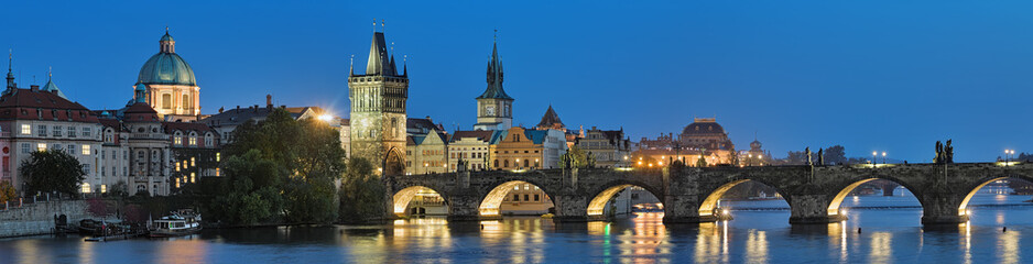 Evening panorama of the Charles Bridge in Prague, Czech Republic, with dome of the Saint Francis of Assisi Church, Old Town Bridge Tower, Old Town Water Tower, dome of the National Theatre