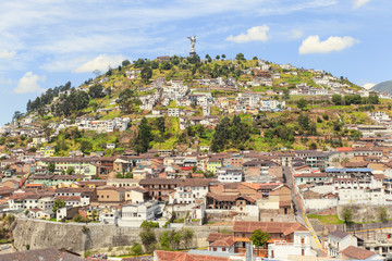 A panoramic view of Quito, Ecuador showcasing the historic center with the iconic Panecillo hill and Virgin statue overlooking the cityscape.