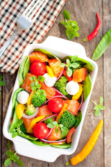 Tasty fried and grilled salmon slices on mixed colorful vegetabl
