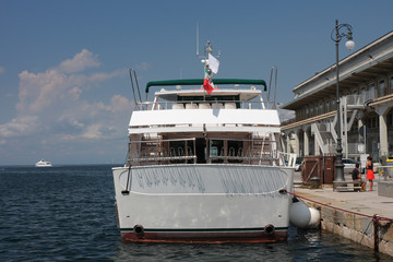 Obraz premium Tourist boat moored in harbor in Trieste, Italy on summer day