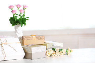 Composition of cute gift boxes and roses on white table