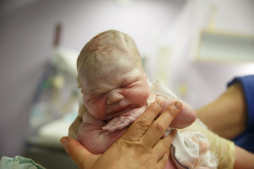 Midwife holding up a vernix covered newborn - 94442849