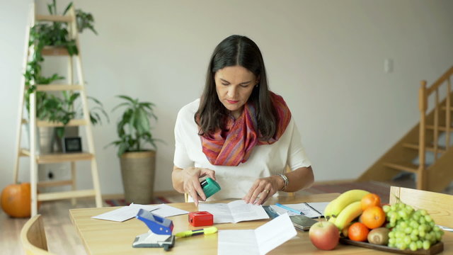 Woman doing stamps and checking documents at home
