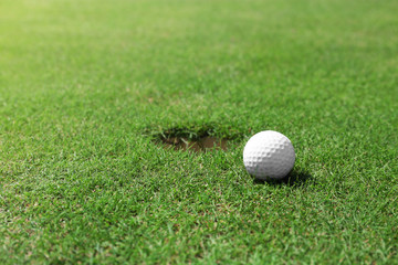 Golf ball on lip of cup on the green golf course
