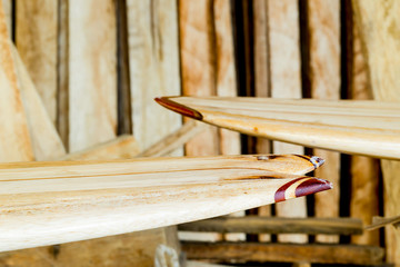 A close-up of a balsa wood surfboard, showcasing intricate details in its manufacture, ready to...