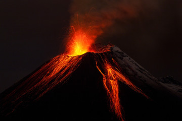 A small active volcano in Ecuador erupting lava and fire, creating a dark explosion amidst the...