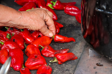 Old woman broiling red peppers