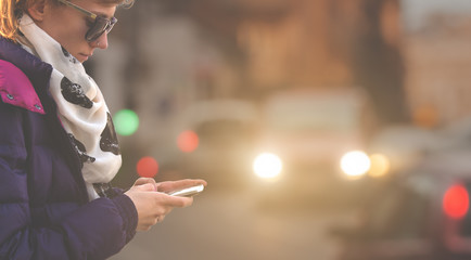 Using cellphone outdoors - with defocused city traffic.