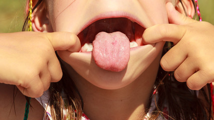 Closeup kid making silly face sticking out tongue