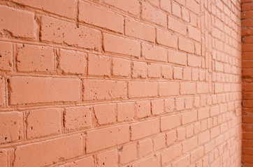 Angle view of a brick wall with a layer of red paint