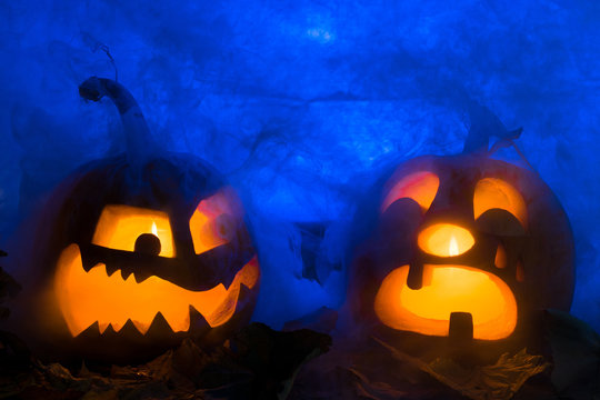 Two pumpkin photo for a holiday Halloween. The spiteful and crying pumpkin against very dense smoke and blue illumination