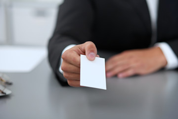 Close-up of  businessman giving a business card, sitting at the table
