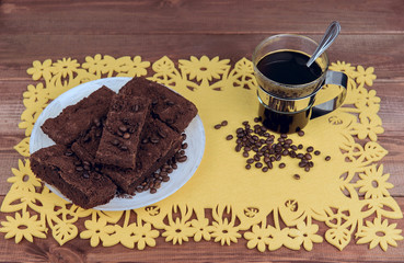 On a wooden table on yellow napkin glass cup of coffee