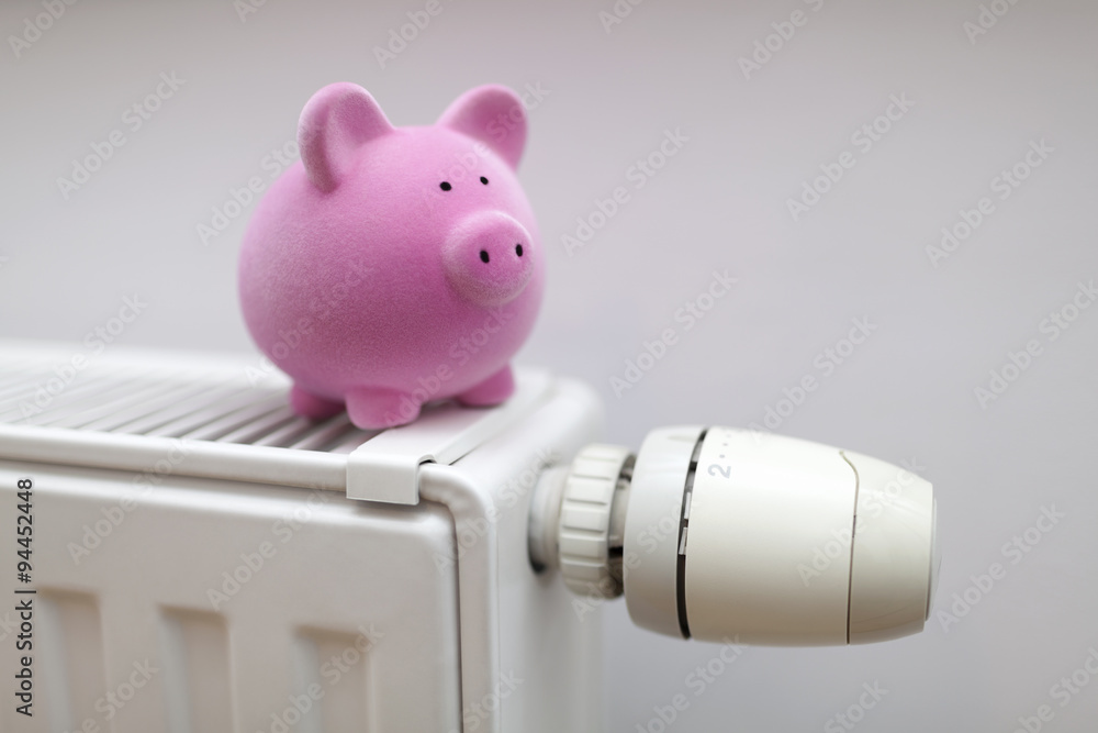 Wall mural pink piggy bank on radiator. energy saving concept.