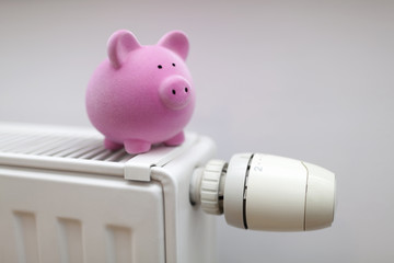 Pink piggy bank on radiator. Energy saving concept.