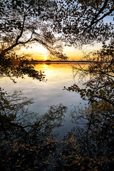 Sunset at the lake, view from the forest edge with reflections a