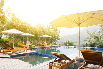 Umbrella chair in hotel pool resort with sunset