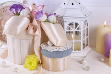 Beautiful composition of ballet shoes, candles, flowers and caskets, close up