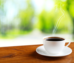 Cup of coffee on table on bright background
