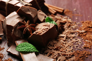 Variety of chocolate pieces, coffee grains and cocoa powder on wooden background