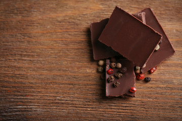 Black chocolate pieces with pepper on wooden background