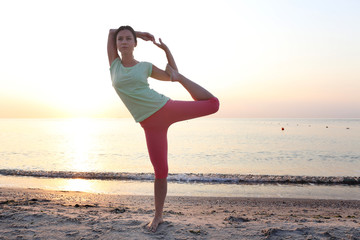 Fototapeta na wymiar Young beautiful woman does yoga on the beach