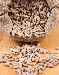 Heap of sunflower in jute bag on wooden table, healthy food