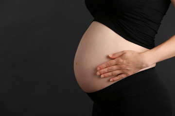 Pregnant woman on black background, close up