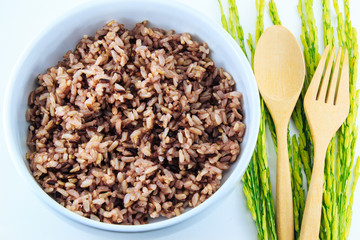 Black rice in bowl and and paddy rice on white background.