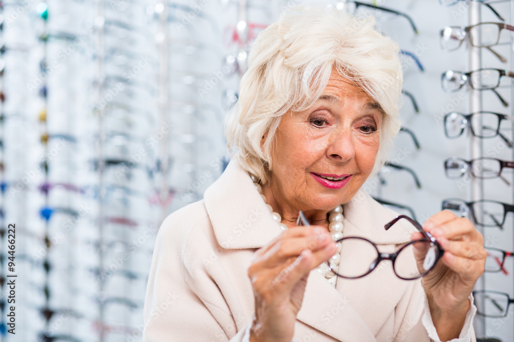 Wall mural Senior woman trying on eyeglasses