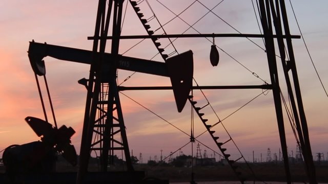 Moving up and down oil pump and derrick in Baku, Azerbaijan, near the Caspian Sea, with nice dark sky background