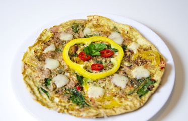 Spinach chili and pepper omelette.A spinach, chili, mint and pepper omelette in a dish in white background. A healthy diet meal omelet.