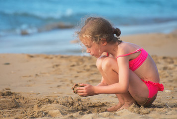 Little girl playing with sand on the beach.