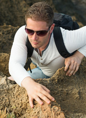 Male tourist with backpack climbing mountains.