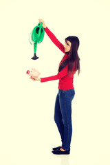 Woman watering piggybank.