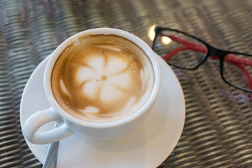 hot latte coffee, white coffee cup on table with eyeglasses