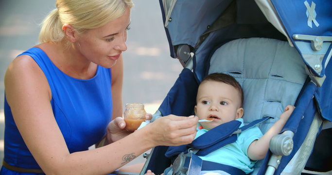Caring mom feeding her lovely baby boy with a spoon 